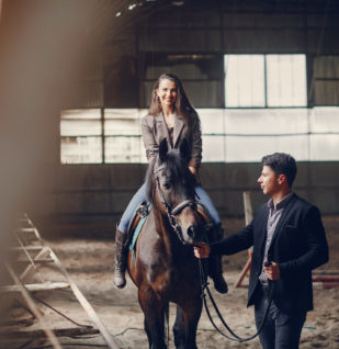 Activité de cohésion d’équipe par l’équicoaching avec une participante à cheval accompagnée d’un coach