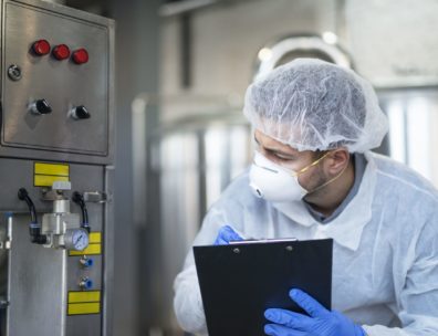 Technicien en tenue d'hygiène contrôlant une ligne agroalimentaire, illustrant la sécurité alimentaire en production